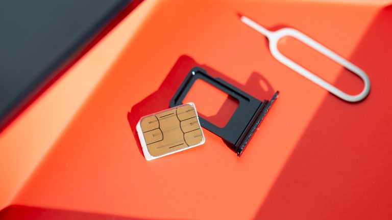 eSIM vs. Klassische SIM, Unterschiede, Vor- und Nachteile Auf einer orangenen Unterlage liegen eine SIM-Nadel, eine Micro-SIM und ein SIM-Kartenhalter für Mikro-SIMs.