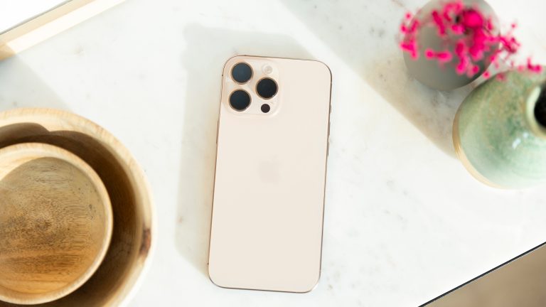iPhone 16 Pro Max, Apples Flaggschiff ausprobiert Ein iPhone 16 Pro Max in Wüstensand liegt mit der Rückseite nach oben auf einem Regal.