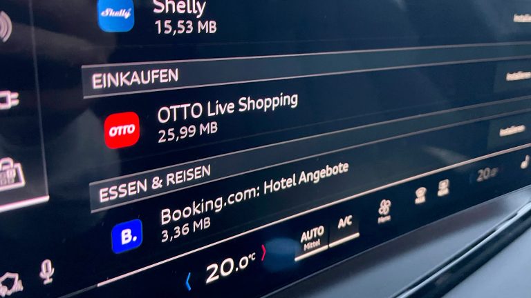 Erlebe OTTO Live Shopping im Audi Q6 e-tron! Eine Nahaufnahme eines integrierten Displays in einem Auto. Darauf ist eine Auflistung der in-Car-Apps zu sehen. In der Mitte steht OTTO Live Shopping.