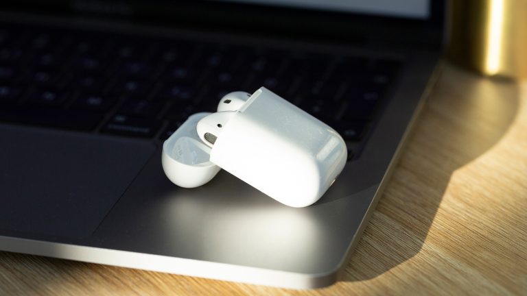 AirPods reinigen, Kopfhörerpflege leicht gemacht Ein geöffnetes Ladecase mit beiden AirPods darin, liegt auf einem geöffneten MacBook.