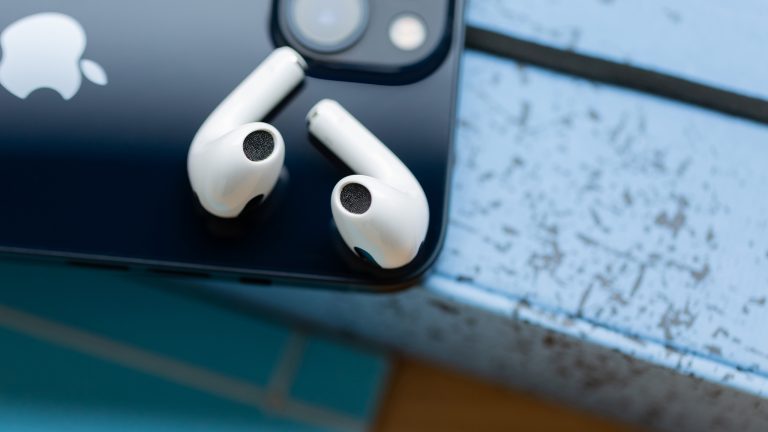 AirPods reinigen, Kopfhörerpflege leicht gemacht Zwei AirPods liegen mit den Lautsprechergittern nach oben auf einem iPhone.