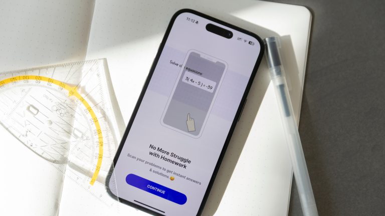 KI App, Mach dir deinen Alltag einfach mit diesen Apps Ein iPhone liegt auf einem geöffneten Notizbuch, daneben ein Stift und ein Geodreieck. Auf dem Display ist die Socratic-App geöffnet.
