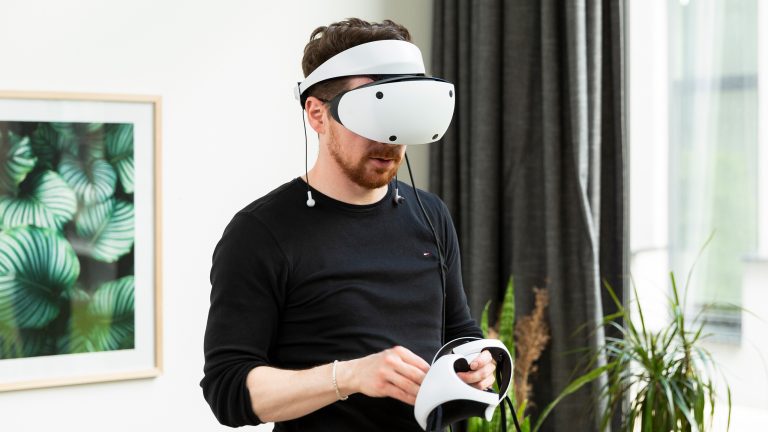 Eine Person steht in einem Wohnzimmer und tr&auml;gt eine PSVR 2.