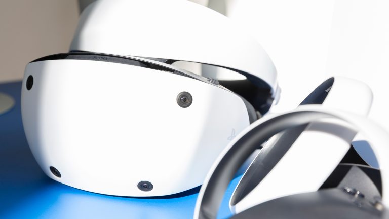 Eine PlayStation VR 2 liegt auf blauem Grund in der Sonne.