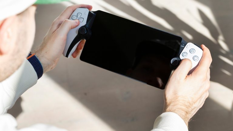 PlayStation Portal, Wie gut das PS-Streaming klappt Eine Person sitzt in der Sonne und hält ein PlayStation Portal in der Hand.