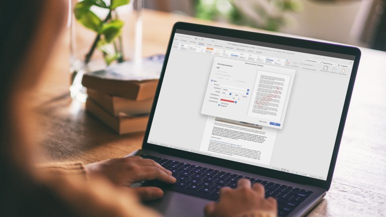 Wasserzeichen in Word einfügen und bearbeiten Eine Person sitzt vor einem Notebook. Auf dem Display ist ein geöffnetes Word-Dokument zu sehen; darüber liegt das Fenster zur Einrichtung eines Wasserzeichens.