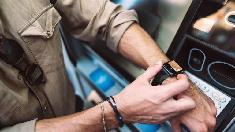 Apple Pay, Bezahlen mit iPhone, iPad und Apple Watch Eine Person hält ihre Apple Watch an ein Kartenlesegerät, um damit den Transport im öffentlichen Verkehr zu bezahlen.