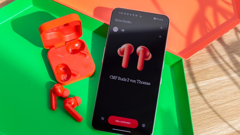 Rundum verbessert, Das CMF Phone 2 Pro und neue Buds im Alltagstest Die CMF Buds 2 in Orange liegen neben einem CMF Phone 2 Pro, auf dessen Display die Kopfhörer zu sehen sind.