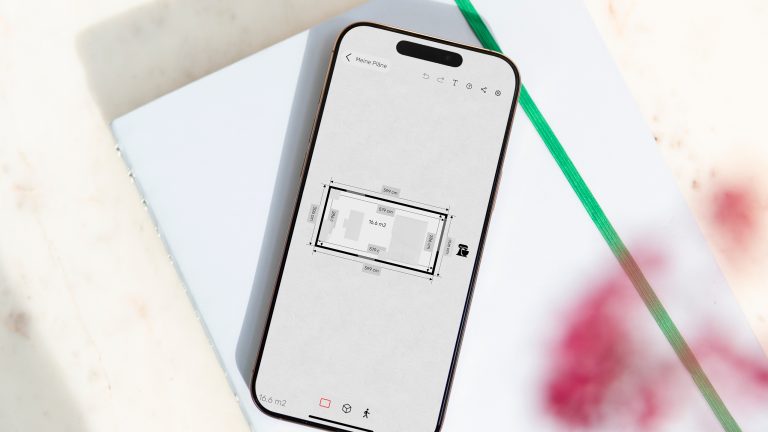 Raumplaner, Richte mit diesen Apps dein Zuhause ein Auf einem iPhone 15 Pro Max ist die Roomle App geöffnet. Sie zeigt den Grundriss eines Raums in 2D inklusive der darinstehenden Möbelstücke.