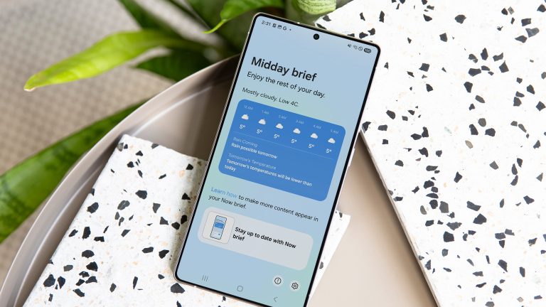 Ein Samsung Galaxy S25 Ultra liegt auf einem Tisch mit gesprenkelten Unterlagen, im Hintergrund eine Pflanze. Auf dem Screen sieht man den Midday Brief, der Infos zum aktuellen Wetter liefert.