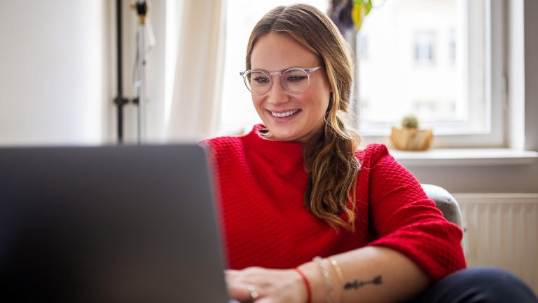 Telegram Web & Desktop, So funktioniert das Chatten ohne Handy Eine Person sitzt auf einem Sofa und schaut in einen Laptop.