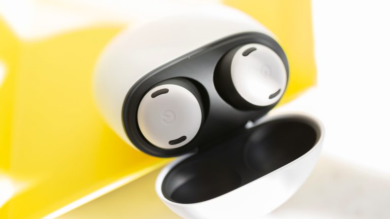 Zwei Pixel Buds Pro in ihrem zugehörigen geöffneten Ladecase, vor einem gelben Hintergrund.
