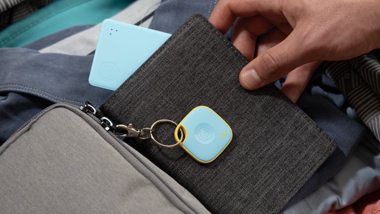 Android Airtag, Welche Airtag Alternativen gibt es? Eine Person hält einen Geldbeutel in der Hand aus dem ein Tile-Card-Tracker herausschaut. Obenauf hängt ein Tile-Tracker an einem Schlüsselkarabiner.