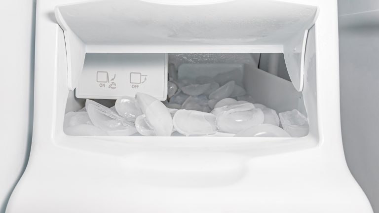 Blick in das Innere einer Eiswürfelmaschine, in der bereits zahlreiche Eiswürfel liegen.