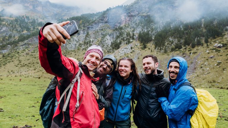 Auf dem richtigen Weg, Wandern mit Wander-Apps Fünf Personen stehen in einer bergigen Landschaft und machen ein Selfie.