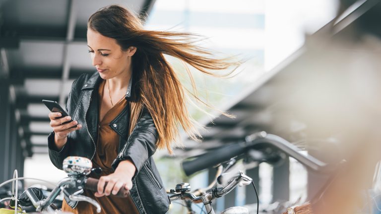 5G, Deutsche Anbieter und Geschwindigkeiten Eine Person mit einem Fahrrad schaut auf ihr Smartphone.