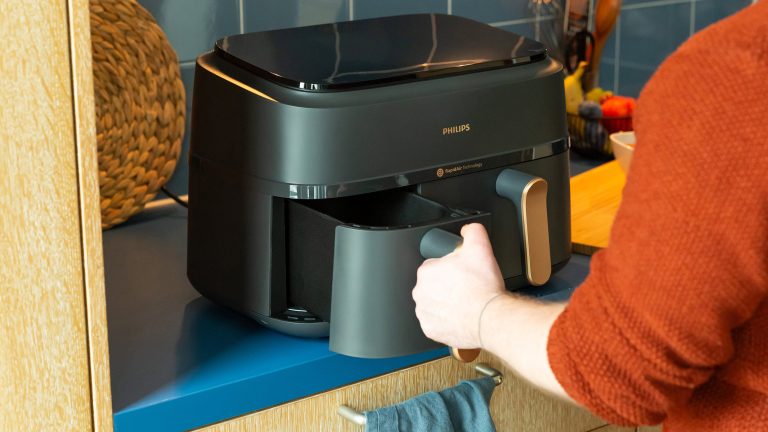 Eine Person öffnet die linke Schublade eines Philips Dual Airfryers.