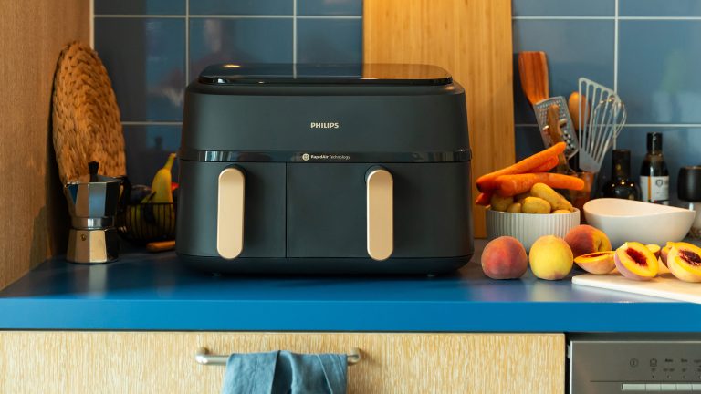 Ein Philips Series 3000 Dual Basket Airfryer steht auf einer Küchenzeile. Daneben und dahinter verschiedene Küchenutensilien.