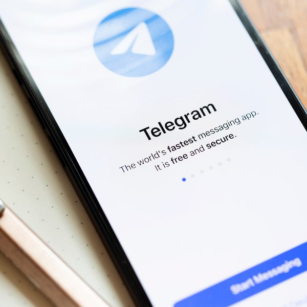 Ein Smartphone auf einem Schreibblock. Links daneben ein Kugelschreiber. Auf dem Screen der Startbildschirm von Telegram.