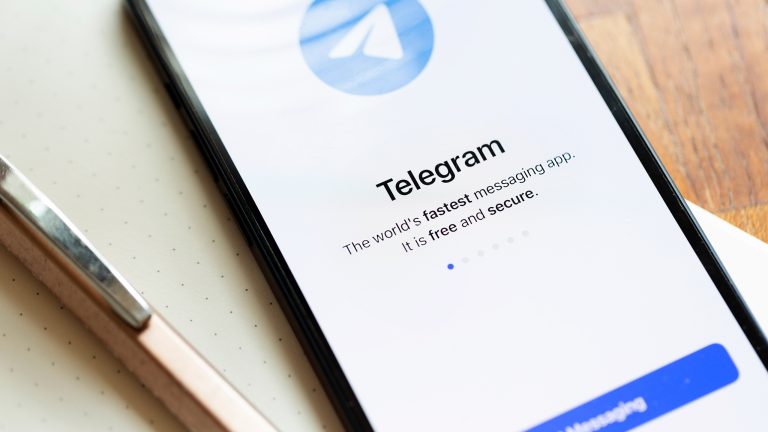 Ein Smartphone auf einem Schreibblock. Links daneben ein Kugelschreiber. Auf dem Screen der Startbildschirm von Telegram.