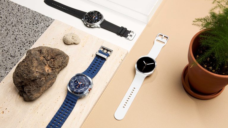 Die Galaxy Watch8, Watch8 Classic und Watch Ultra liegen auf hellen Flächen neben einem Stein und einer Pflanze.