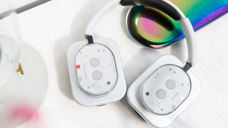 Die Nothing Headphones (1) liegen mit eingedrehten Ohrmuscheln auf einem Tisch.