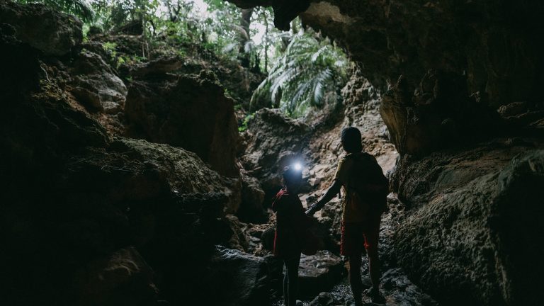 Urlaub mit Kindern, 12 Gadgets für die Kleinen Eine Person und ein Kind stehen in einer Felsgrotte. Das Kind trägt eine Stirnlampe am Kopf.