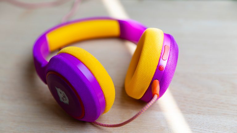 Urlaub mit Kindern, 12 Gadgets für die Kleinen Seitansicht der Tigerbuddies, die auf einem holzfarbenen Tisch liegen. Im Fokus steht der Lautstärkeregler sowie der On-/Off-Knopf an der Seite der Kopfhörer.