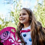 Ein Kind hält freudestrahlend eine pinke Schultüte in den Händen.