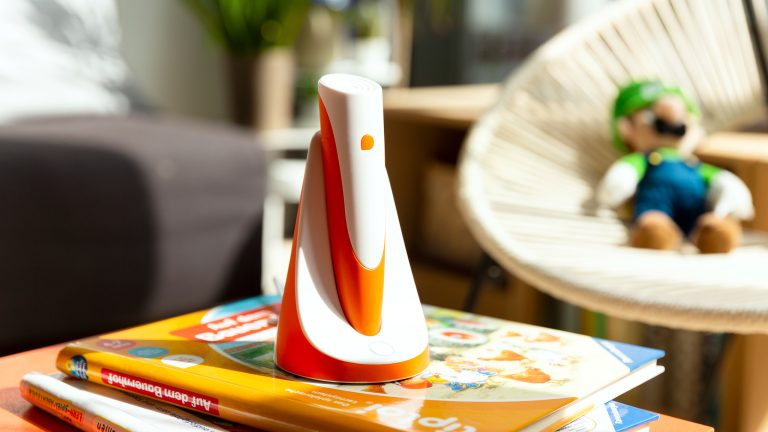 Geschenkideen zum Schulanfang, 8 clevere Produkte für einen smarten Start Ein tiptoi-Stift steht auf einem Stapel Bücher in der Ladestation. Im Hintergrund ist ein Kinderzimmer zu sehen.