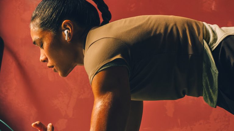 Eine Person in Sportkleidung führt einen Plank aus. Sie trägt dabei AirPods Pro 3.