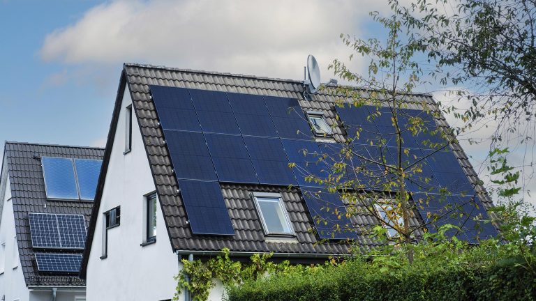 Energie sparen, So hilft dir dein Smart Home Kosten zu sparen Aufnahme eines Einfamilienhauses mit Spitzdach auf dem eine Solaranlage installiert ist.