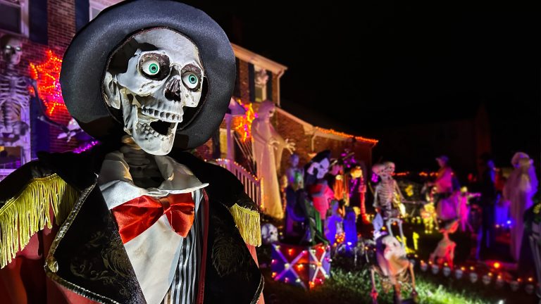 Halloween-Deko für Balkon und Garten, Elektrische Highlights für ein schauriges Ambiente Ein Skelett in einem Anzug steht vor einem gruselig geschmückten Haus.