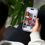 Der Blick über die Schulter einer Person auf ein Handy auf ihrem Bein, das den Instagramfeed von Otto.de zeigt.