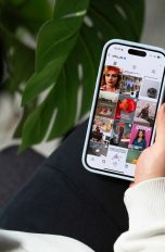 Der Blick über die Schulter einer Person auf ein Handy auf ihrem Bein, das den Instagramfeed von Otto.de zeigt.