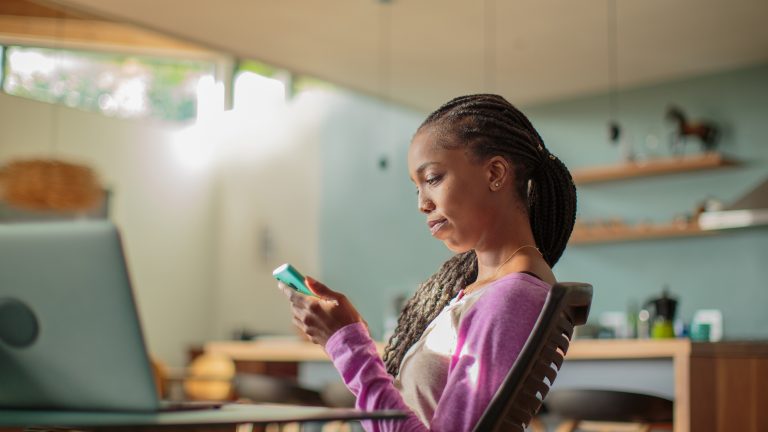Klarna-Konto löschen, So löst du deinen Account beim Bezahl-Dienstleister auf Eine Person sitzt an einem Schreibtisch in ihrem Zuhause und schaut auf ihr Smartphone.