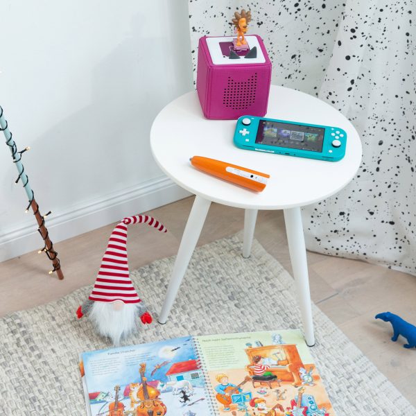 Eine Toniebox, eine Nintendo Switch Lite und ein Tiptoi-Stift auf einem kleinen Tisch.